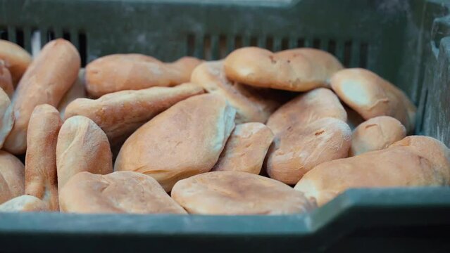 Freshly baked white bread loaves in plastic container, bread delivery to local bakery store, assortment of bread for selling