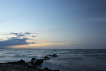 Fototapeta na wymiar Smooth seascape with rocks at dusk.