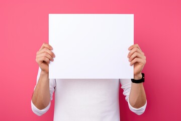 man holding a blank placard poster paper in his hands on pastel pink background - obrazy, fototapety, plakaty