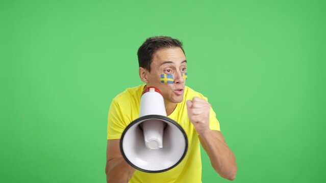 Excited man with swedish flag on face using a megaphone