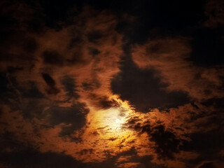 Fire in the sky, the moon behind the clouds bathes the night in mystical light