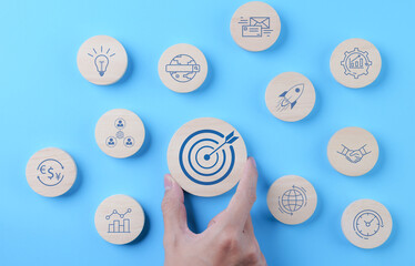 The concept of business goal and marketing target. Man hand holding wooden block with bullseye icon...