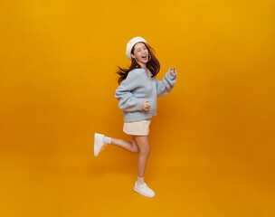 Cheerful positive Asian teenage girl running with laugh face looking at camera isolated on yellow...