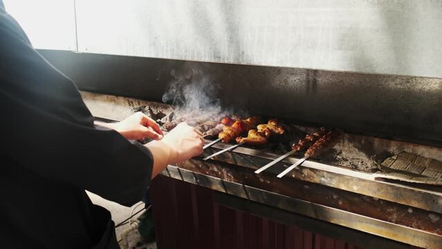 A kebab maker turns over kebabs of chicken, meat, liver and vegetables fried on the grill
