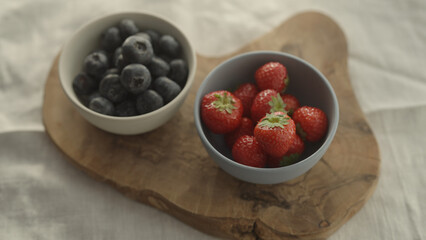 fresh blueberries and strawberries in ceramic bowls with natural light