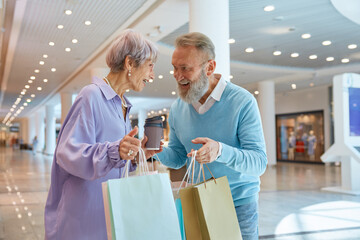 Smiling senior couple in shopping mall after purchases