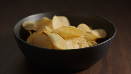 potato chips in black bowl on wood table
