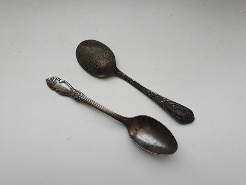 Two vintage cupronickel spoons on a white background.