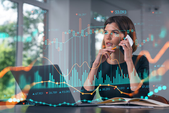 Pensive attractive beautiful businesswoman in working on laptop, talking phone, office workplace in background. Forex graph and charts hologram icons. Concept of market trading and research. - Powered by Adobe