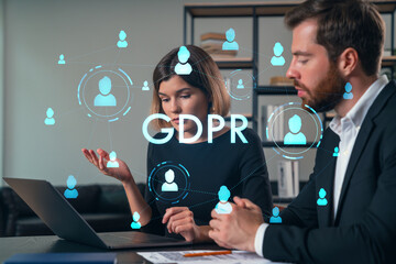 Thoughtful businesspeople typing on laptop at office workplace. Concept of team work, business education, internet surfing, brainstorm, project information technology. GDPR hologram