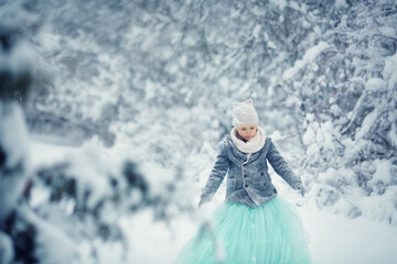 Girl in blue dress in a snowy winter park