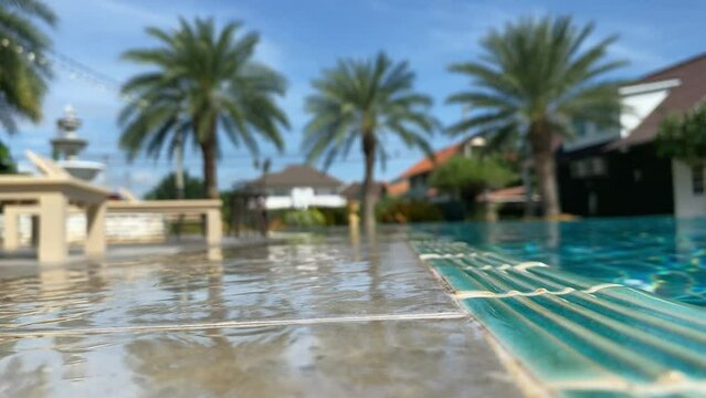 Low angle shot poolside swimming pool outdoor with blurred palm tree summer time blue sky. Relaxing and calmness concept