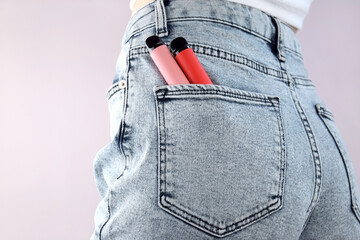 A set of multi-color disposable electronic cigarettes in a jeans pocket.