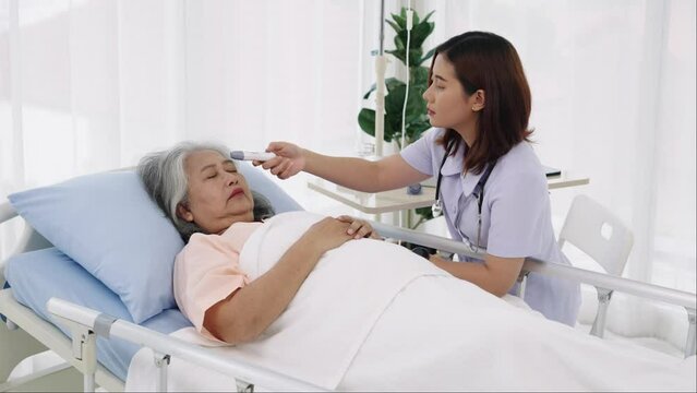 Handheld shot, Elderly Asian patient admitted to hospital She has a cough and fever. Nurse uses a digital thermometer to take her temperature. Nurses care for patients in hospitals or clinics...