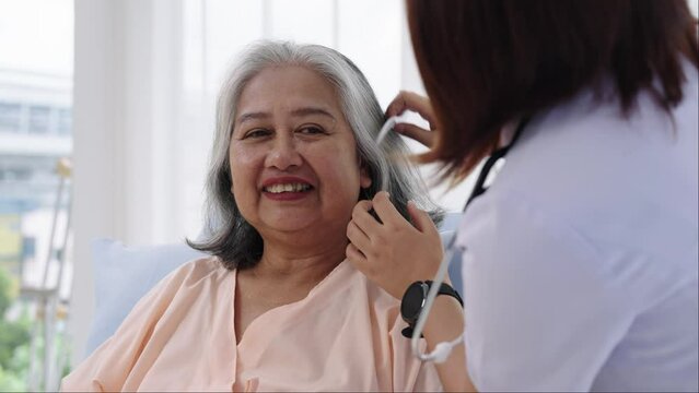 Close-up A nurse combs the hair of an elderly Asian patient and offers a pep talk.