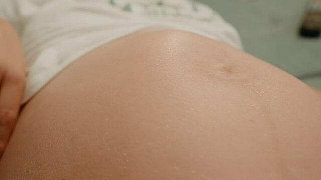 Close up pregnant woman playing with baby kicking from inside the womb. Woman checking for abnormal baby movement.