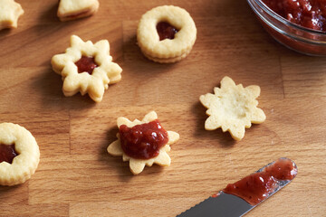 Filling traditonal Linzer Christmas cookies with strawberry jam, closeup