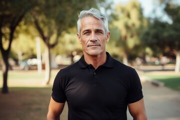 Portrait of a content man in his 50s donning a classy polo shirt against a vibrant city park. AI Generation