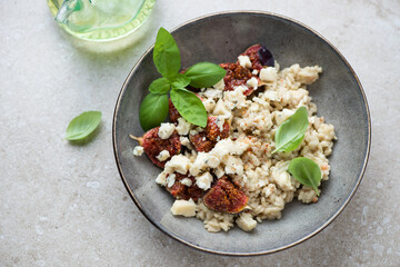 Grey plate with figs and blue cheese risotto on a beige stone background, horizontal shot, high angle view
