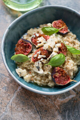 Risotto with fig fruits, blue cheese and fresh basil in a green bowl, middle close-up, vertical shot