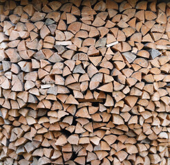 Firewood stacked near the wooden wall of old hut. Many chopped logs of firewood close up