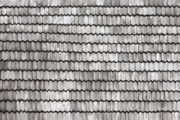 Gray wooden roof tiles background texture. A close up of old gray roof covered with wooden tiles or shingles