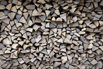 Firewood stacked near the wooden wall of old hut. Many chopped logs of firewood close up