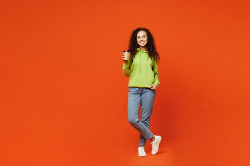Fototapeta na wymiar Full body young woman of African American ethnicity she wear hoody casual clothes hold takeaway delivery craft paper brown cup coffee to go isolated on plain red orange background. Lifestyle concept.