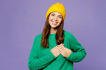 Young smiling cheerful woman she wear green sweater yellow hat casual clothes put folded hands on...