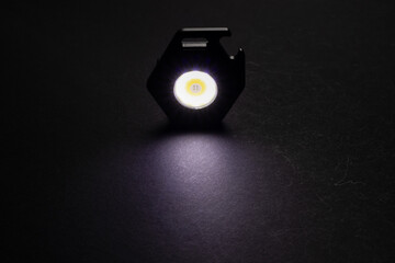 LED Flashlight Keychain and a beam of light in darkness. A modern led lamp with bright projection...