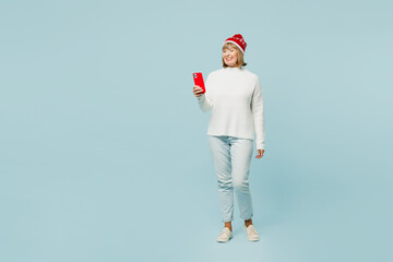 Full body merry smiling elderly woman 50s years old wear sweater red hat posing hold in hand use...