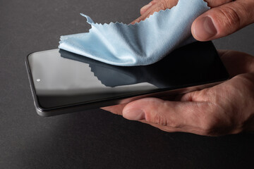 Germs elimination. Cleaning the smartphone screen with a fiber cloth from dirt dust and other external factors.