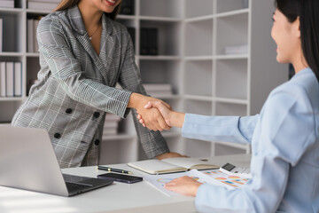 Two businesswoman shaking hands after discussion about new business project and deal together