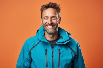 Obraz premium Portrait of a smiling man in his 40s wearing a windproof softshell against a pastel or soft colors background. AI Generation