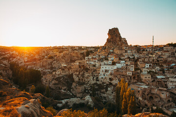 The sun's last rays illuminate the unique landscape of Cappadocia, casting a golden glow over the...