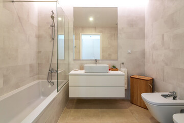 Modern bathroom design with bath and shower cubicle and wash hand basin. and a bidet with a closed...