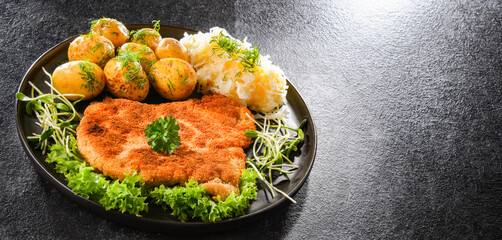 Pork cutlet coated with breadcrumbs with potatoes and cabbage