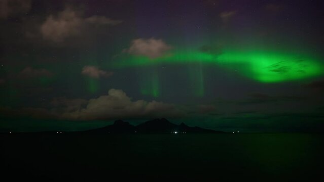 With a view towards the iconic mountainous island Landegode north of Bod&oslash; in September, an aurora was dancing above the clouds in stormy weather, starting off the aurora season.