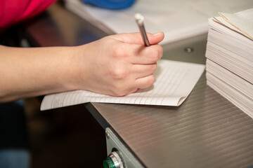 A woman's hand holds a pen at her workplace.