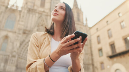 Traveler girl using looking mobile phone sitting on the steps of an old building in the historical part of an old European city, Close up