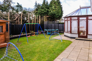 Enclosed family rear garden with childrens swings, football nets, trampoline, playhouse and conservatory
