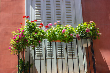 Fototapeta na wymiar A balcony window with a huge number of mix potted green plants. Fresh flowers decorate exterior of apartment building, facade of apartment house in summer. Home garden. Planting plant-pots on terrace.
