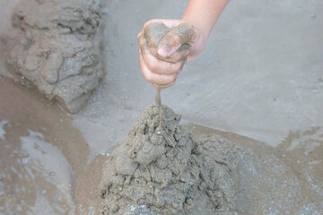 The boy's hand plays a sand pile on the beach.