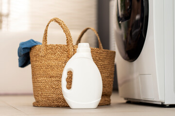White bottle bottle laundry detergent, basket with clothes standing in laundry room. Mockup - obrazy, fototapety, plakaty
