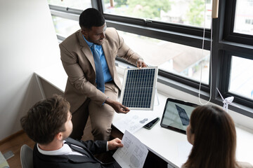 African American businessman and team business working with solar panel and tablet computer at...