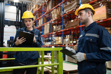 Caucasian business woman workers using clipboard checking Kraft paper stock while standing on scissor lift in warehouse