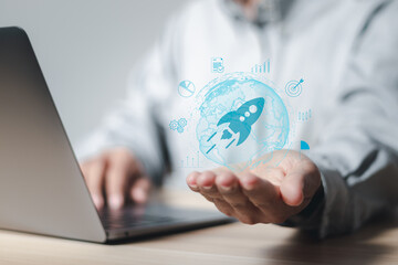 Startup business concept, Businessman use laptop and holding rocket icon for fast start up business. Plan work strategies and business success.