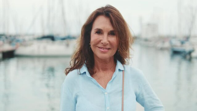 Smiling beautiful middle aged woman standing in port looking at camera