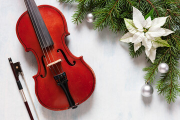 Fototapeta na wymiar Old violin and fir-tree branches with Christmas decor and white poinsettia. Christmas, New Year's concept. Top view, close-up..