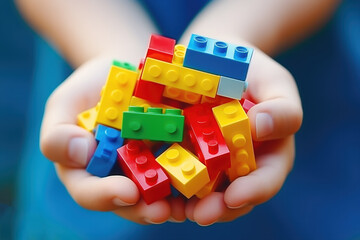 Close-up of child's hands holding an assortment of multicolored building blocks, emphasizing creativity and playful learning